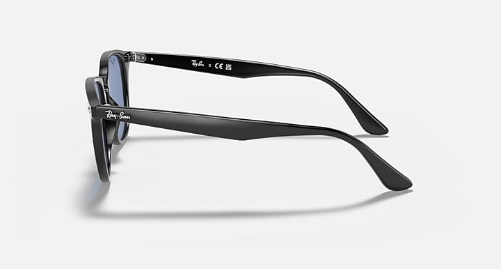 Black oversized round sunglasses, side profile with curved temples and blue lenses