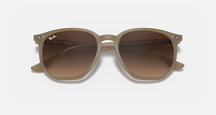 Light brown hexagonal sunglasses with dark brown tinted lenses and sculpted temples