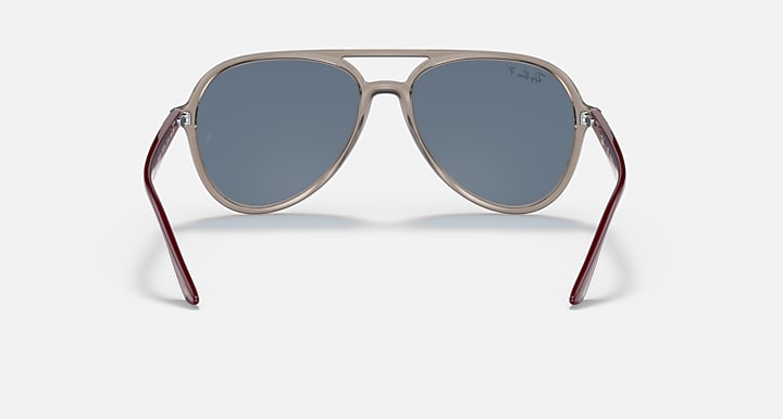 Ray-Ban aviator sunglasses with beige frame, maroon accents, and blue-tinted lenses.