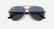 Ray-Ban aviator sunglasses with beige frame, maroon tips, and blue tinted lenses.