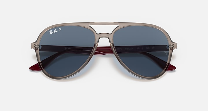 Ray-Ban aviator sunglasses with beige frame, maroon tips, and blue tinted lenses.