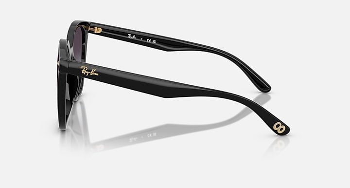 Black sunglasses side view with gold logo on temple and dark tinted lens frame.
