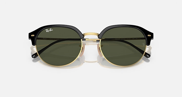 Front view of round sunglasses with black top frame, gold rim, and dark lenses