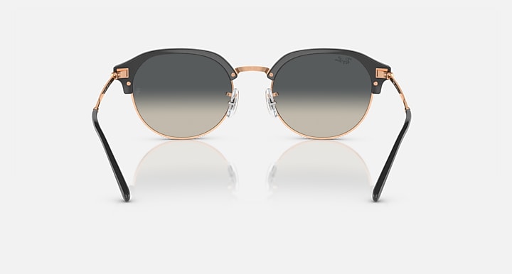 Front view of round sunglasses with black frame, gold trim, and gray gradient lenses