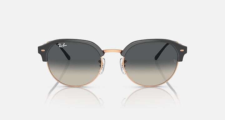 Round sunglasses with black frame, rose-gold outer rim, and gray tinted lenses