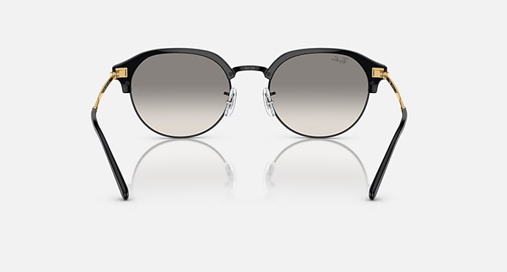 Round sunglasses with black frame and gold accents at the temples; grey lenses.