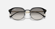 Round sunglasses with black frame and smoke-grey lenses, front view with gold hinges.