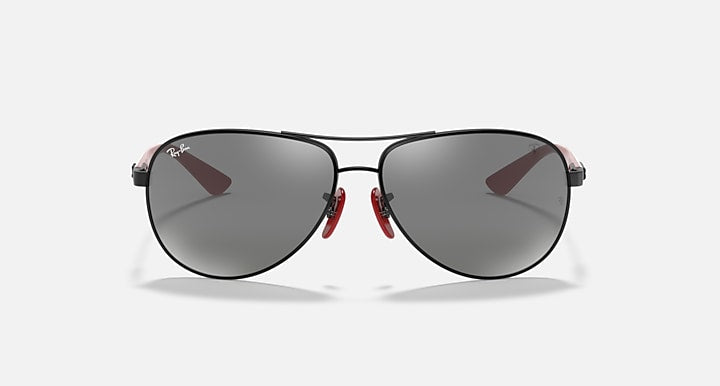 Ray-Ban aviator sunglasses front view, black frame with grey mirror lenses and red hinge.