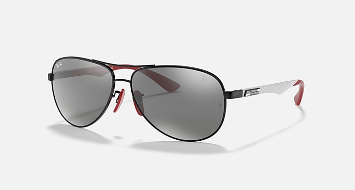 Ray-Ban aviator sunglasses side view, black frame with grey mirror lenses and red accents.