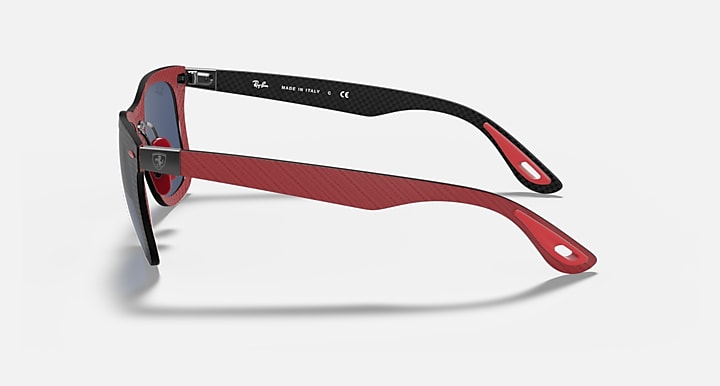 Red and black sunglasses side profile with blue lens and metal hinge