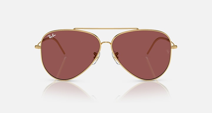 Ray-Ban aviator sunglasses, gold frame with maroon lenses and nose bridge.