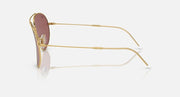 Ray-Ban aviator sunglasses in gold with maroon lenses, side view.