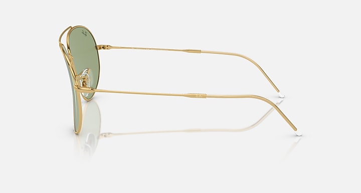 Ray-Ban aviator sunglasses in gold with green lenses, side profile.