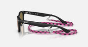 Ray-Ban Junior Wayfarer sunglasses, side view; black frame with pink patterned strap.