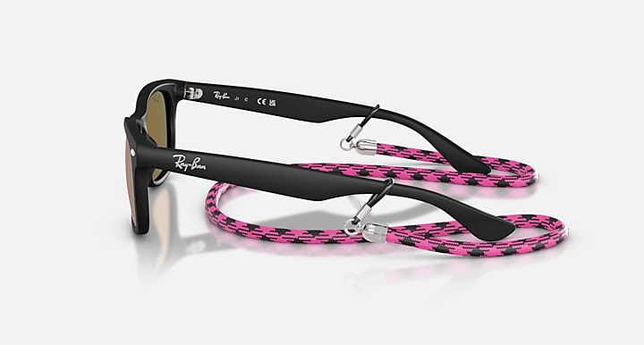 Ray-Ban Junior Wayfarer sunglasses, side view; black frame with pink patterned strap.