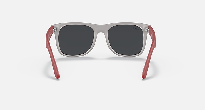 Sunglasses with gray frames and dark lenses, red rubber arms, and metal accents