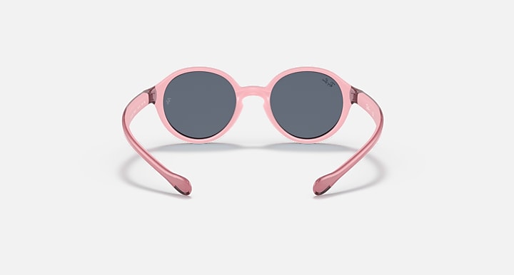 Ray-Ban round sunglasses with pale pink frame and dark gray lenses.