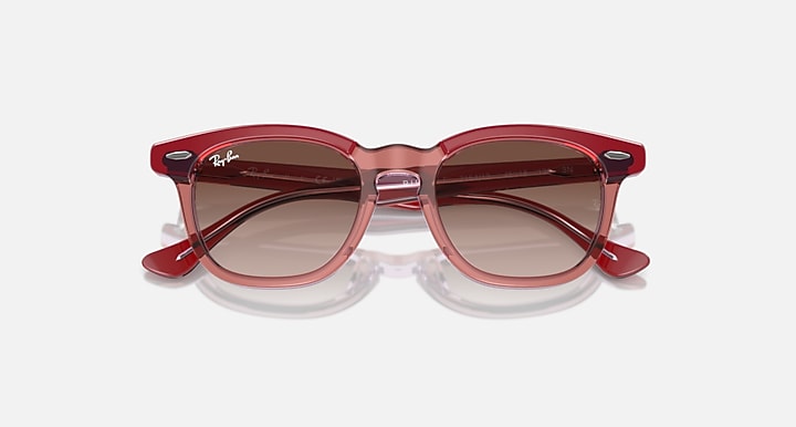 Ray-Ban transparent red cat-eye sunglasses with brown gradient lenses, angled view