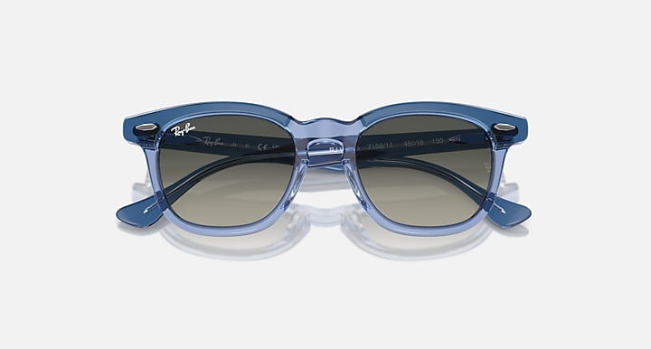 Ray-Ban RJ9098S sunglasses with light blue transparent frame and dark blue lenses, angled front view