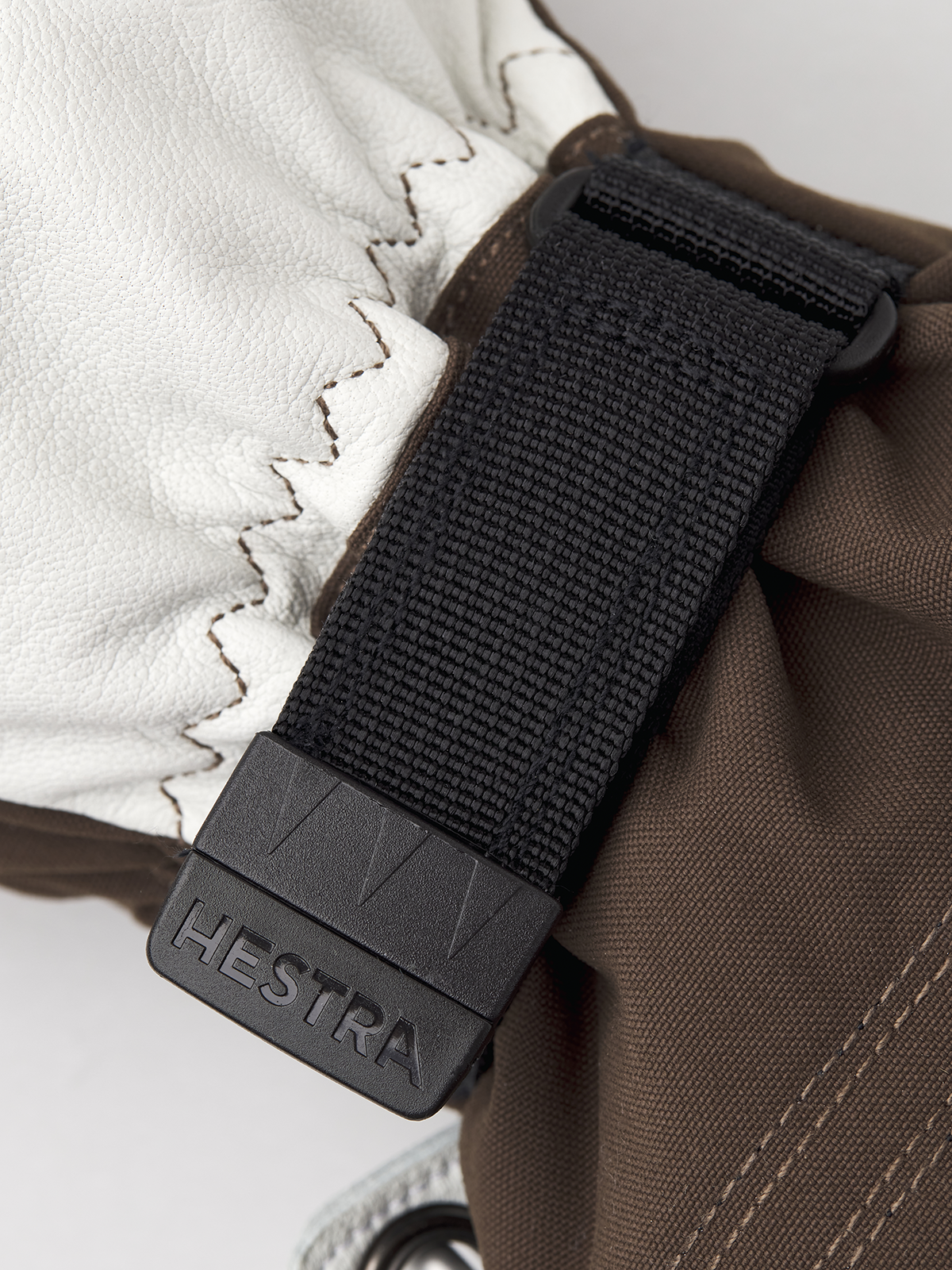 White ski mitten with black HESTRA-branded strap clip and woven texture