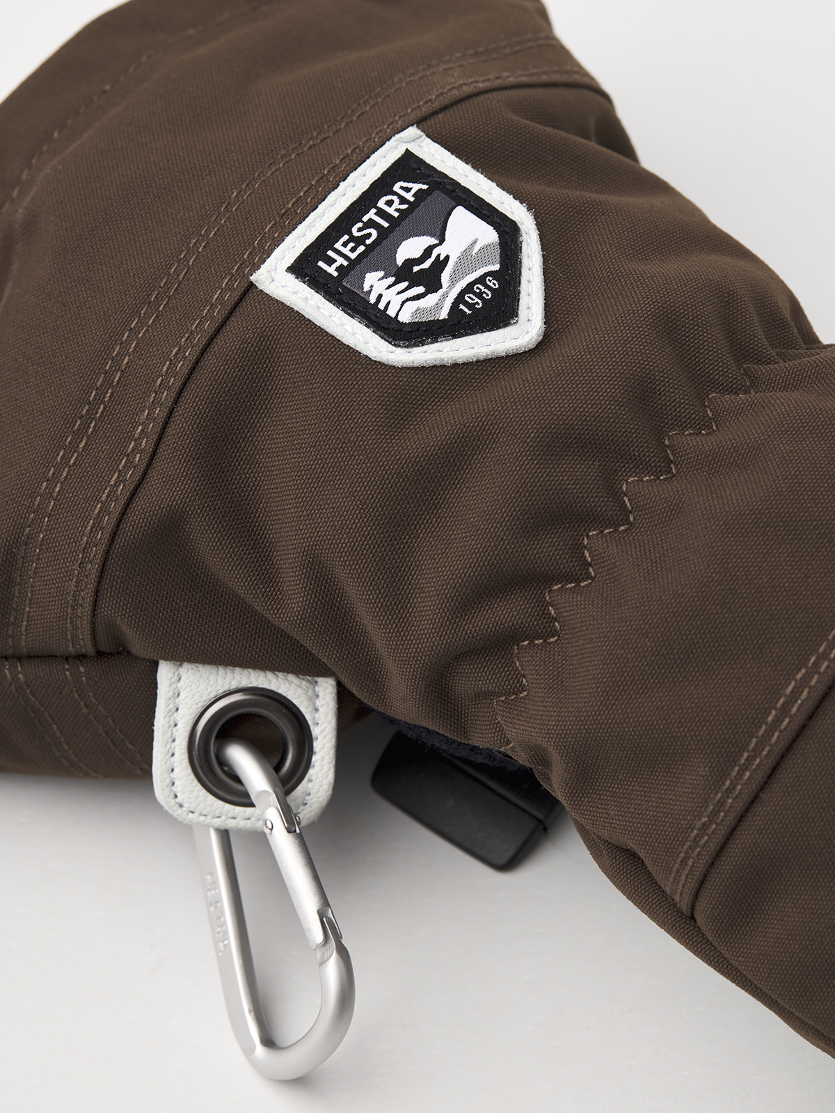 Brown ski mitten with HESTRA logo patch and metal carabiner ring