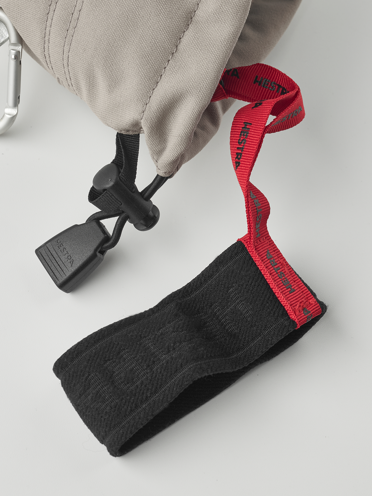 Close-up of glove cuff with black wrist strap and red fabric loop detail