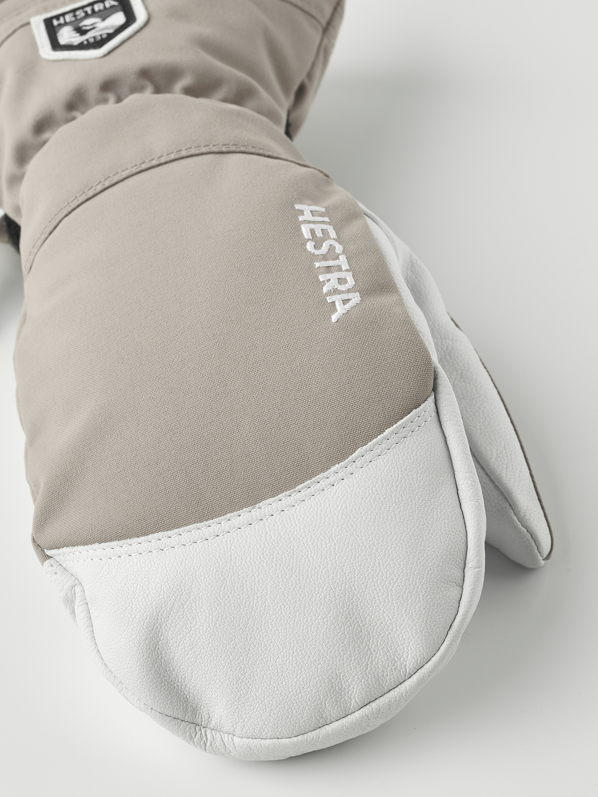 Light grey and white ski mitten with white leather palm and Hestra logo