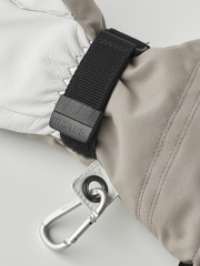 Beige leather ski glove cuff with black strap and metal carabiner.