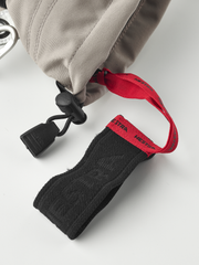 Beige ski mitten with black and red wrist strap and hanging carabiner