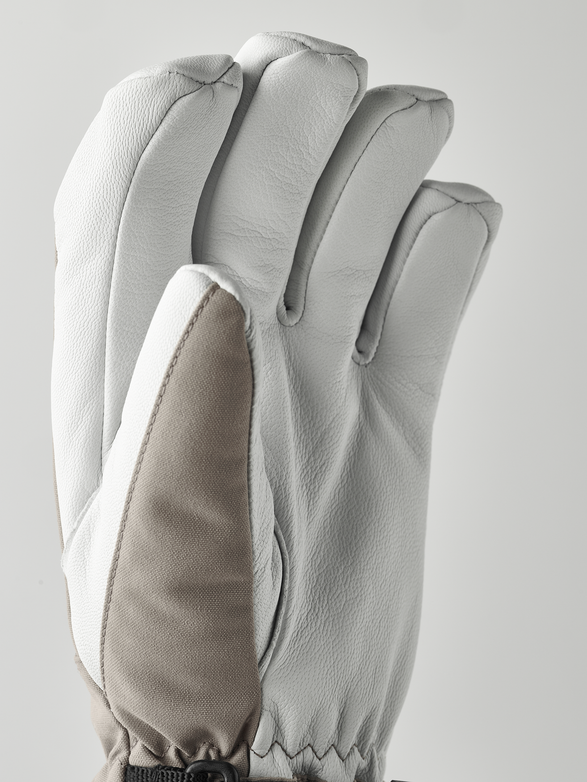 Light gray ski gloves with textured knuckle seams and beige inner panel detail