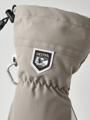 Tan Hestra ski glove with logo patch and metal carabiner-style clip