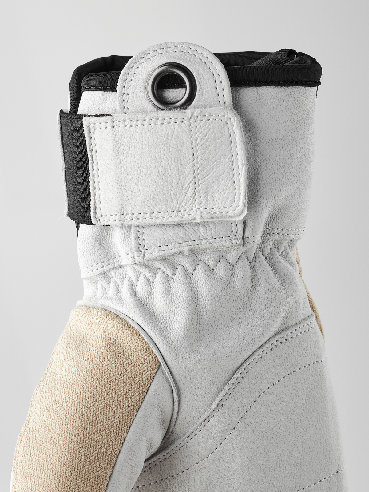 White 3-finger leather glove cuff close-up with metal ring and elastic top