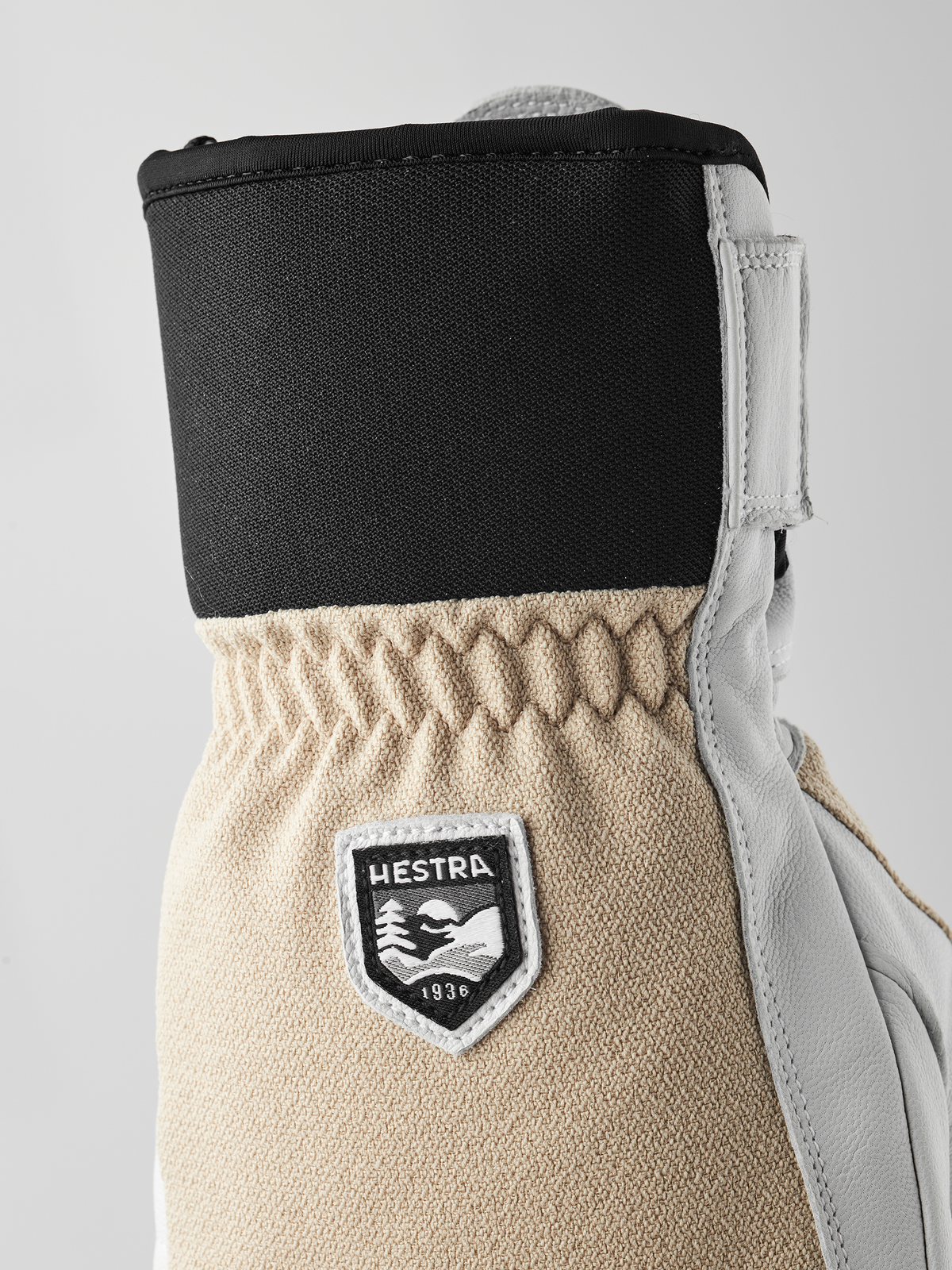 Leather and textile patrol gloves with black upper and beige cuff, Hestra patch.
