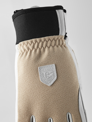 Tan textured patrol glove with dark cuff, Hestra shield patch, and stitched seams