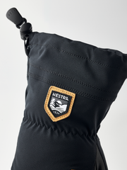 Black junior glove cuff with HESTRA leather-trim logo patch and drawcord