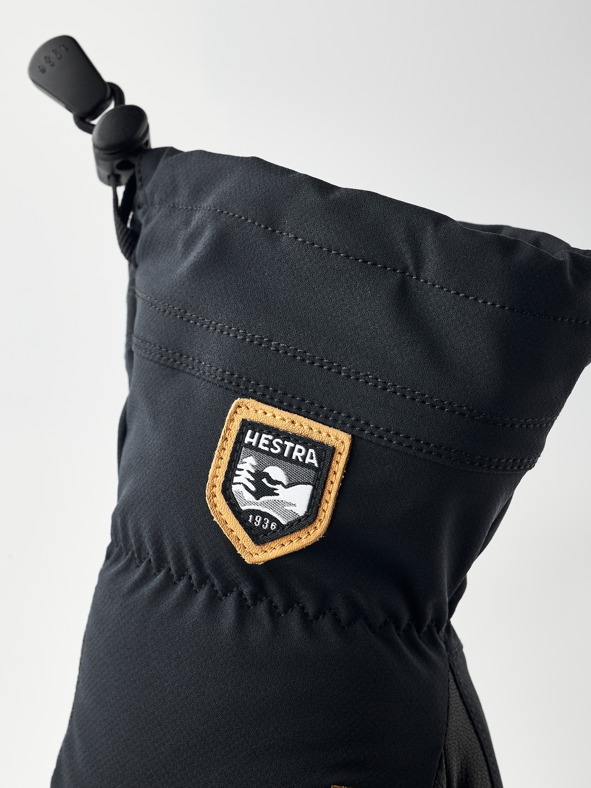 Black junior glove cuff with HESTRA leather-trim logo patch and drawcord