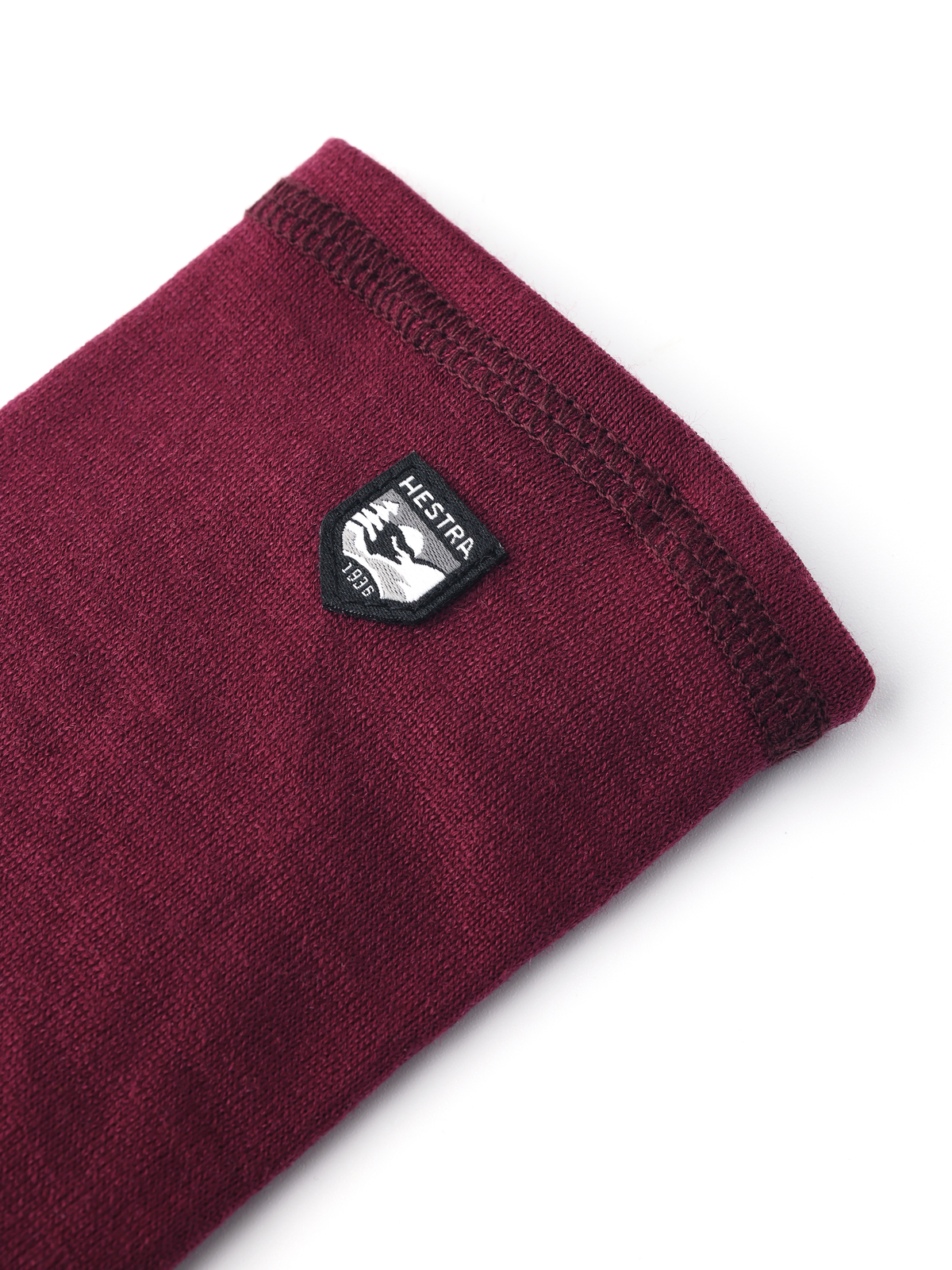 Bordeaux merino wool glove liners with small Hestra logo patch on folded cuff