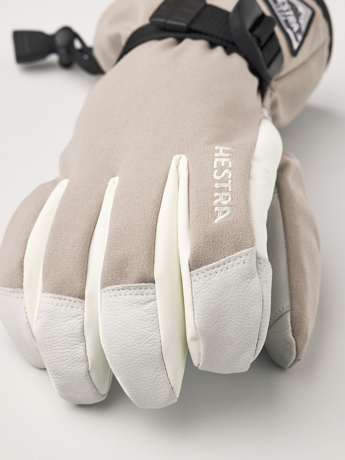 Close-up beige powder gauntlet gloves with white leather palms and logo embroidery