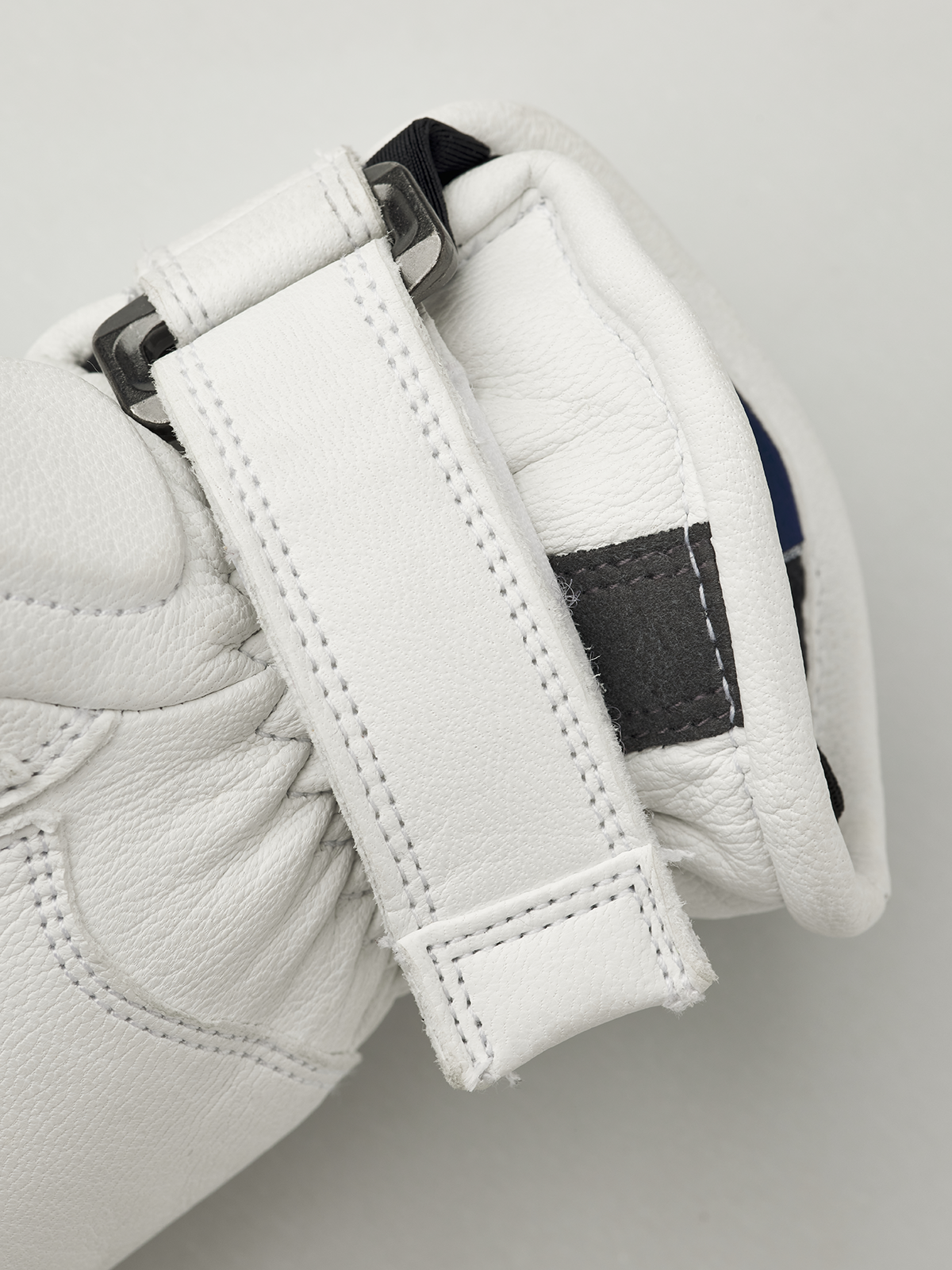 Kids racing gloves cuff detail, white leather strap with black patch and stitched edges