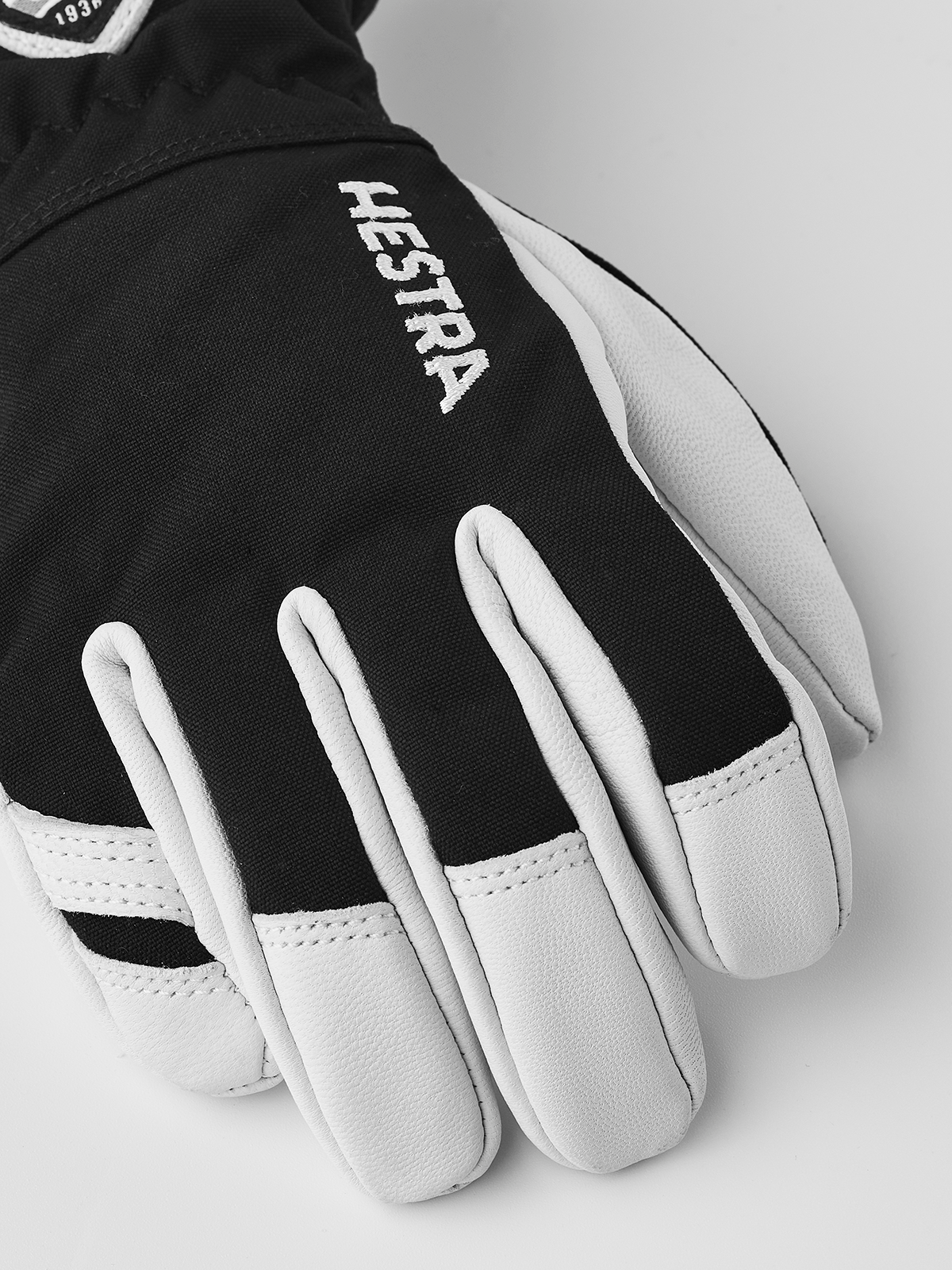 Hestra junior ski gloves in black with white leather palms and Hestra branding on back