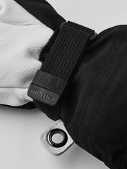 Kids ski gloves close-up: white and dark leather palms with black strap and logo patch