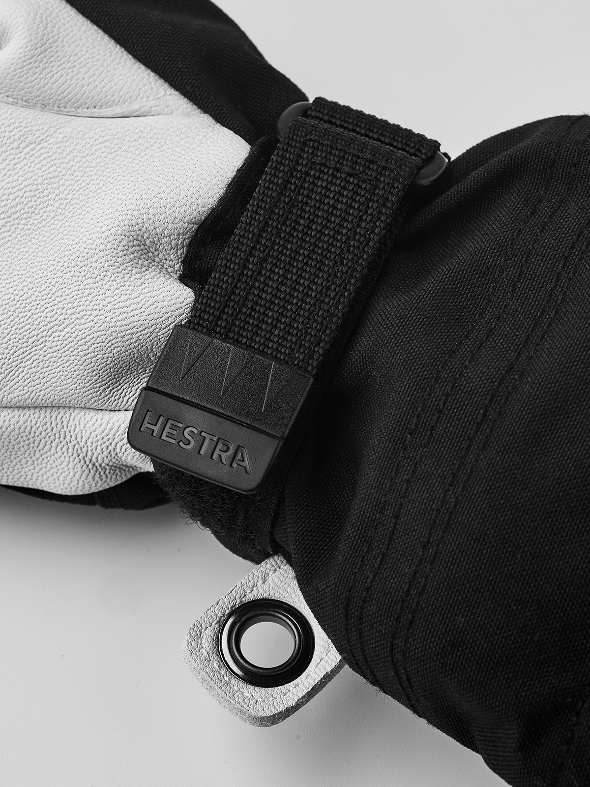 Kids ski gloves close-up: white and dark leather palms with black strap and logo patch