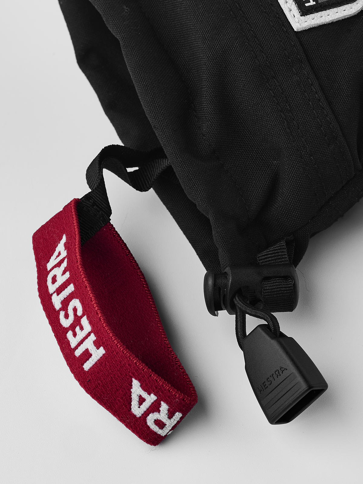 Kids black ski gloves with red fabric wrist strap and quick-release clip