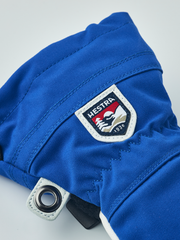 Kids royal blue ski gloves with Hestra logo patch and metal grommet