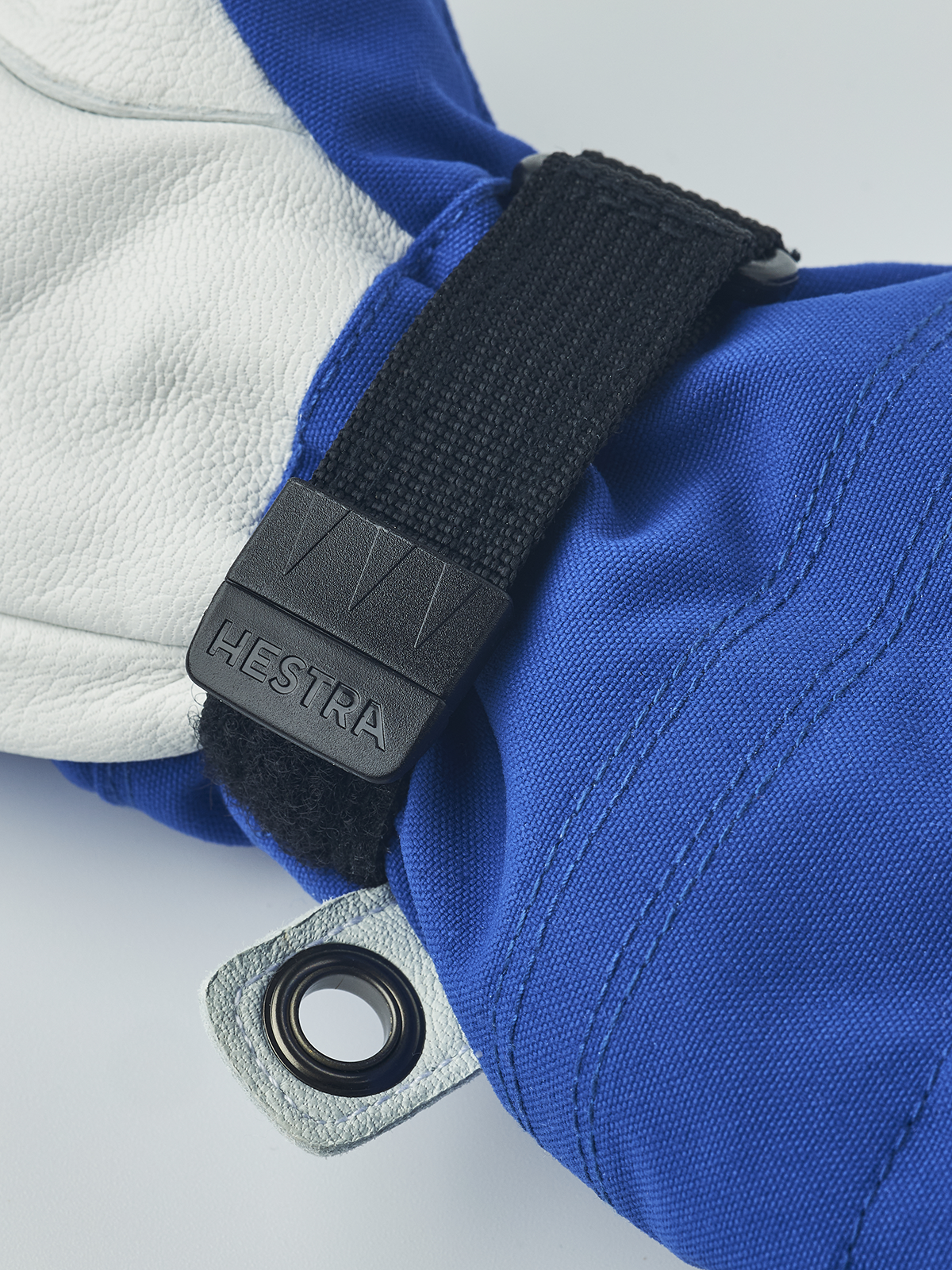 Kids ski gloves close-up: blue fabric cuff with black strap and grey fabric loop