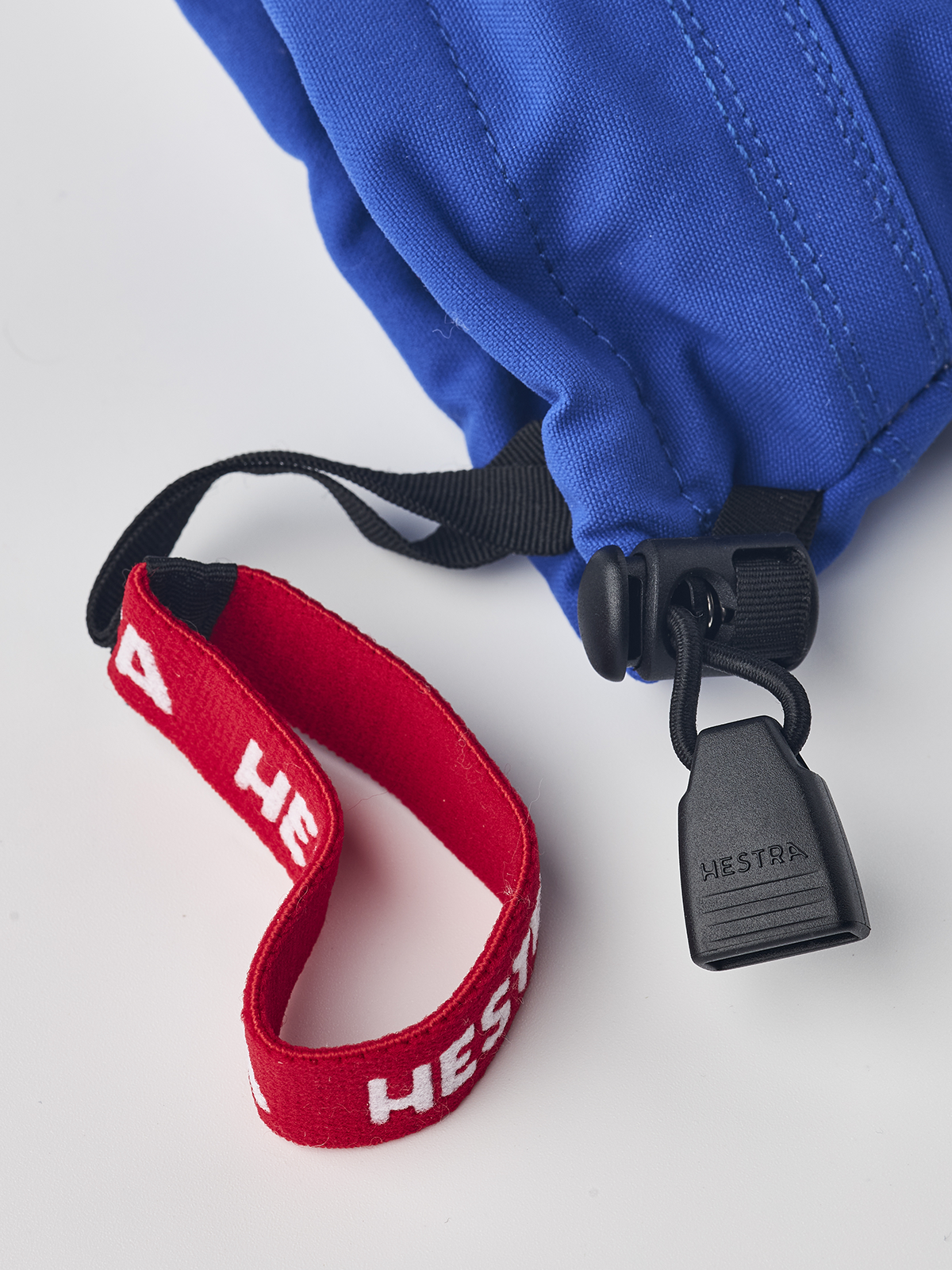 Kids ski gloves detail: blue sleeve with black strap, red logo trim, and white lining