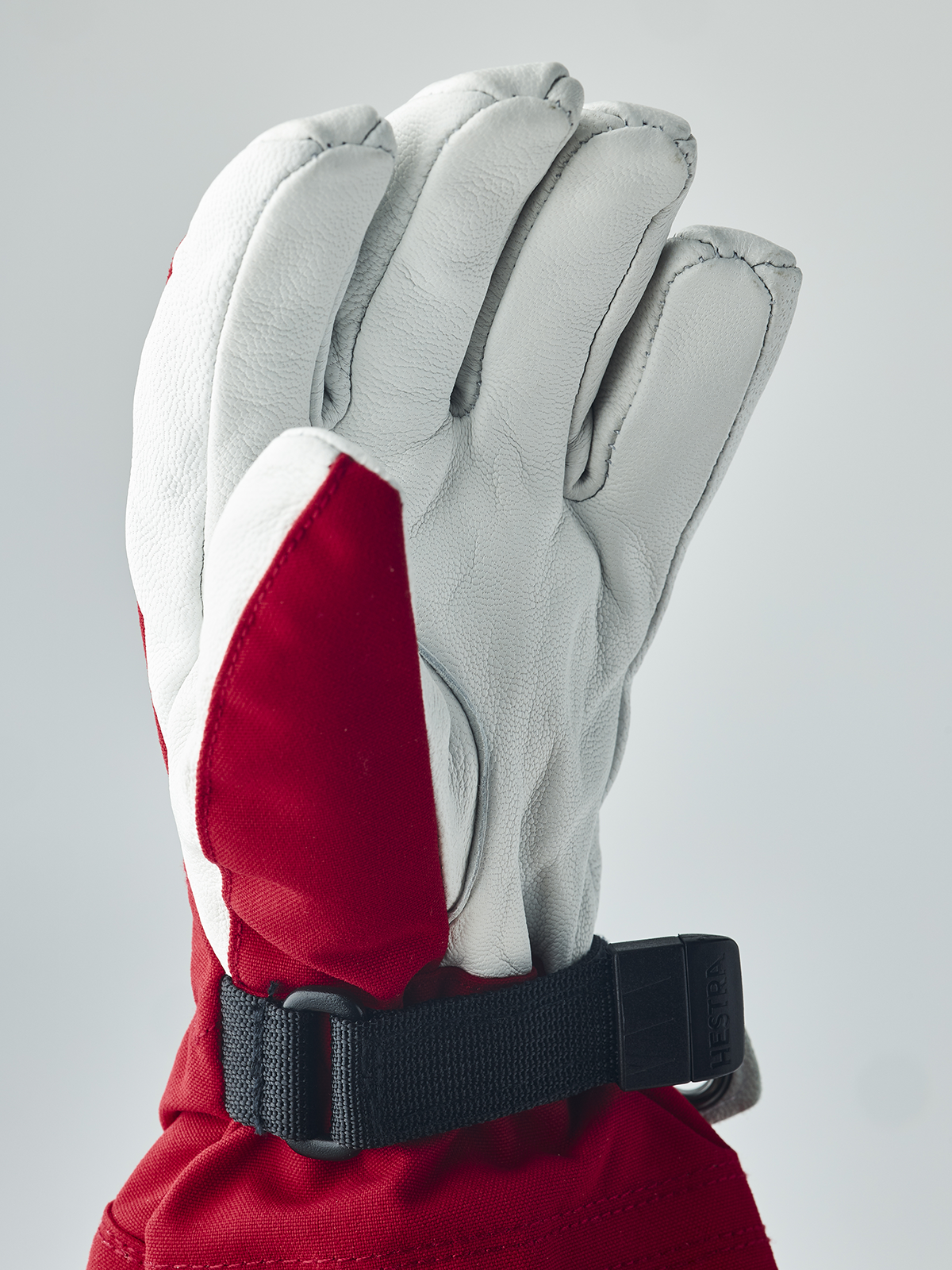 White ski junior glove with red cuff panel and adjustable black wrist strap