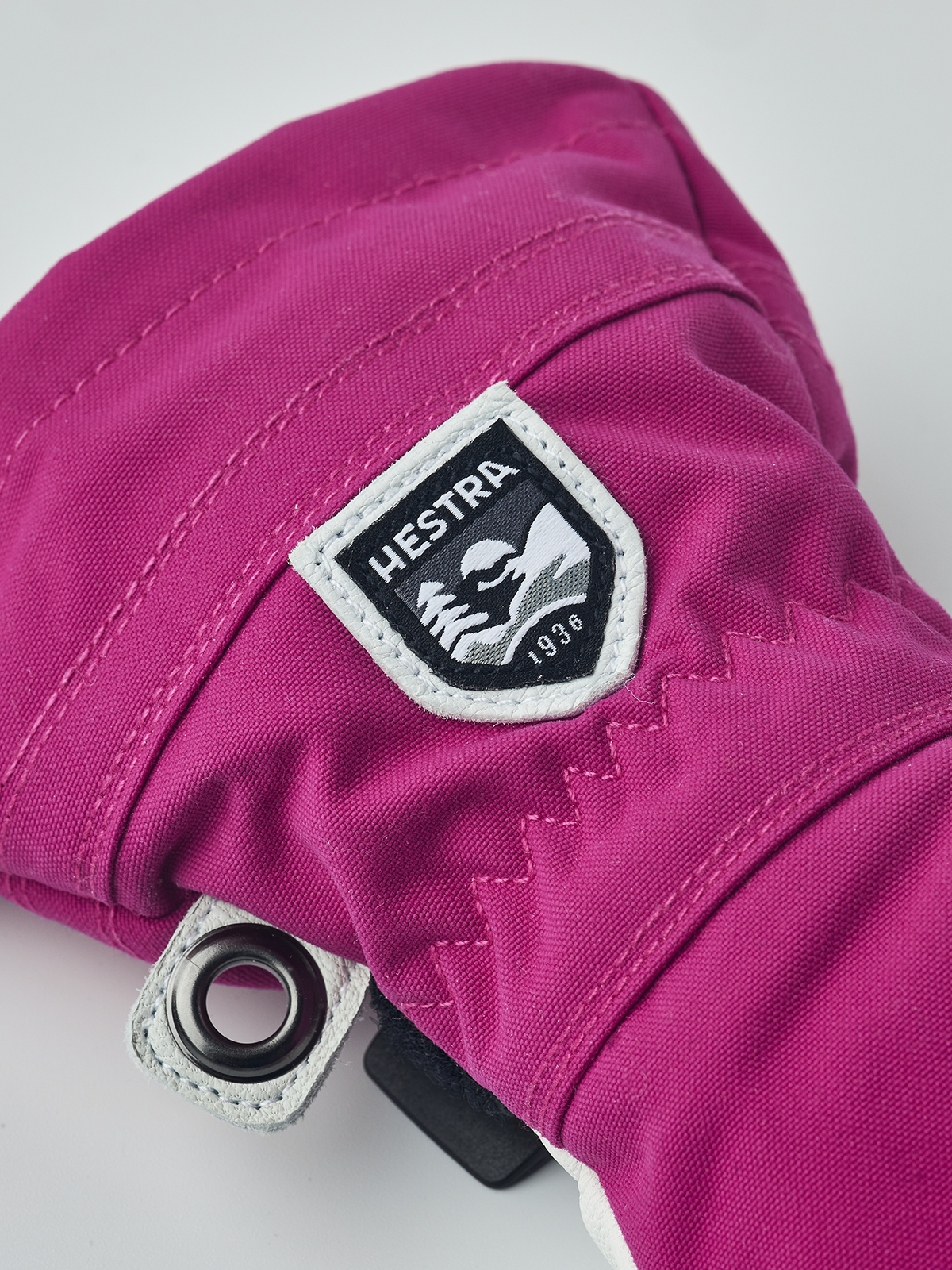 Hestra junior ski gloves in fuchsia with Hestra logo patch and metal eyelet