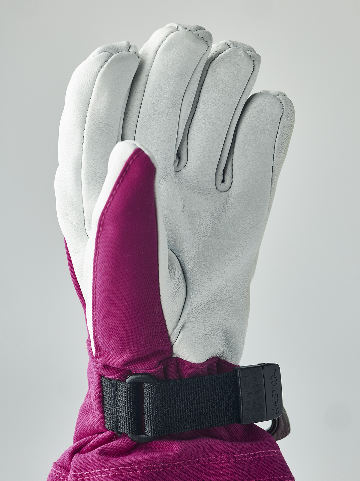 Fuchsia and white ski junior glove with black wrist strap and stitched seams