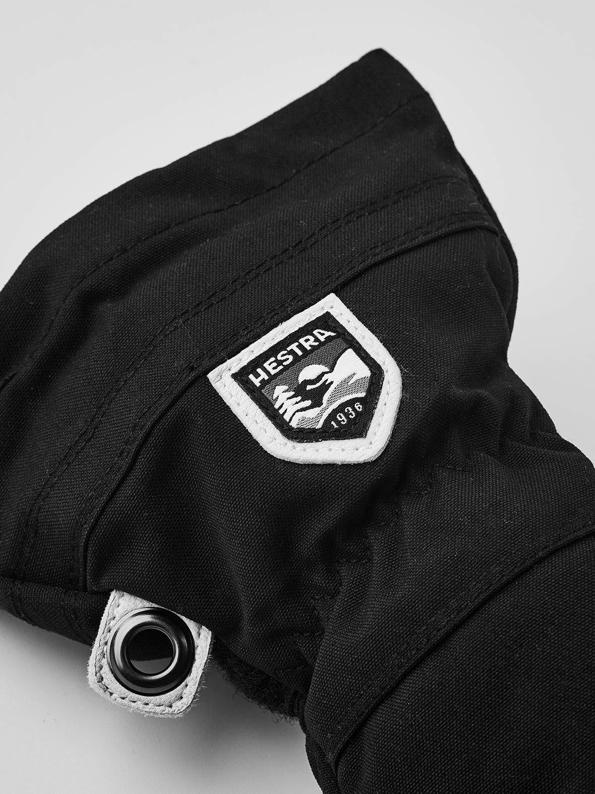 Junior ski glove in black with Hestra patch and metal eyelet detail